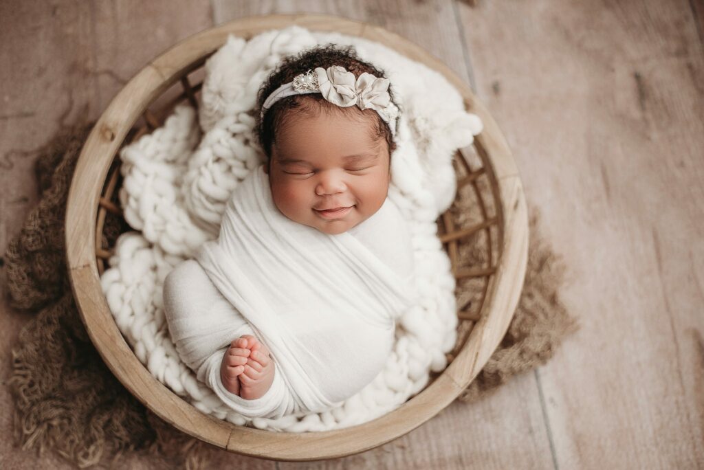newborn baby girl posed in a bowl for her newborn photoshoot in atlanta ga studio. Baby in a bowl prop, baby girl smiling for her newborn photography session, atlanta newborn photography