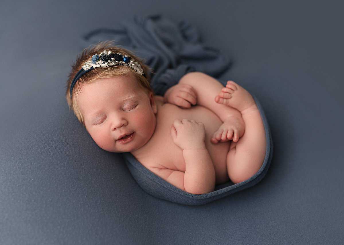babygirl professionally photographed on the color blue, blue tieback newborn photography, atlanta newborn photoshoot in studio, posed newborn photography