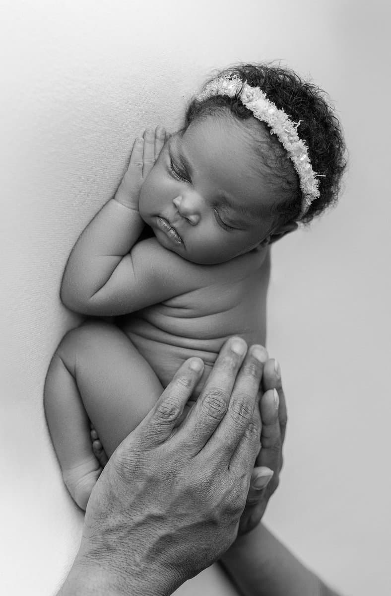 baby photography, black and white newborn portraits, newborn with parents hands, sleeping newborn girl during photoshoot, newborn beaded tieback, newborn photography session in atlanta