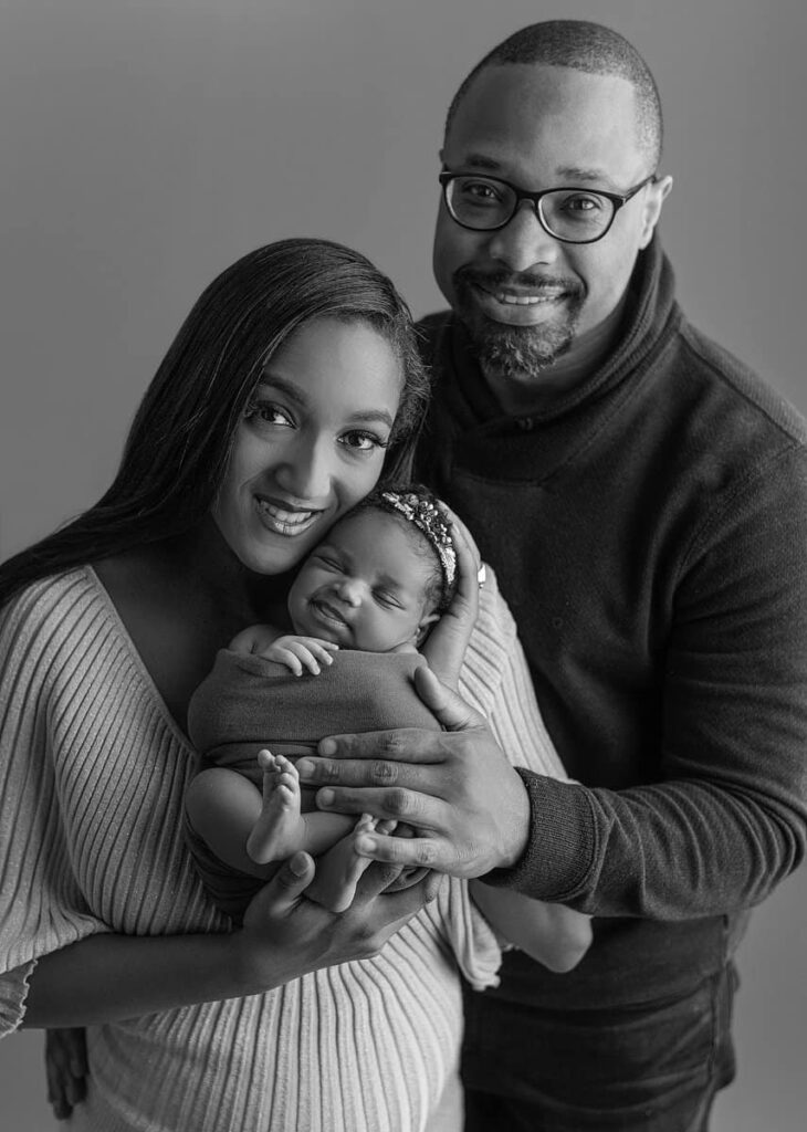 smiling newborn baby girl posed with parents, traditional newborn family poses in studio, newborn baby photography, photography studios in atlanta