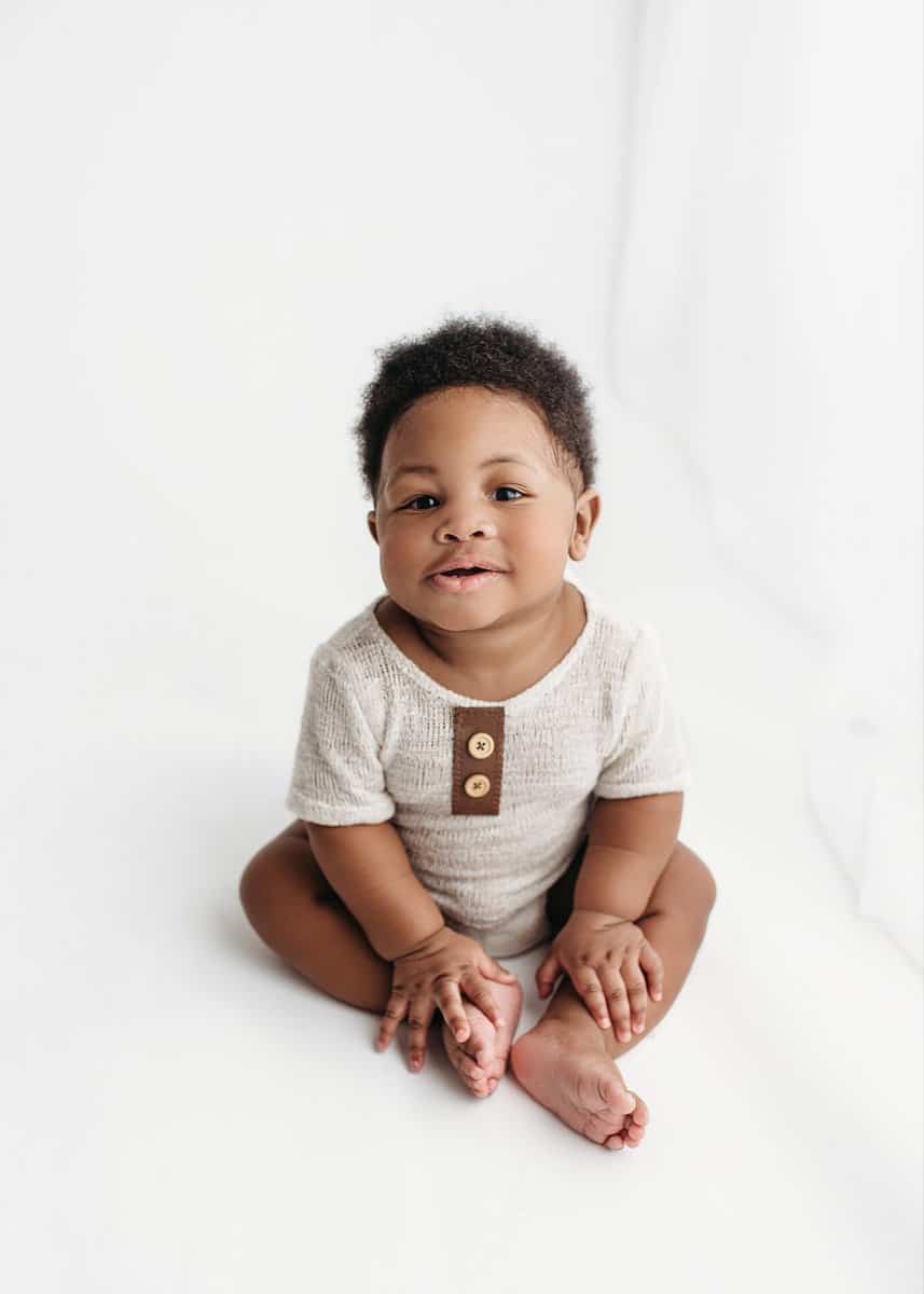 baby boy smiling for his milestone photography session at an all white studio in atlanta ga