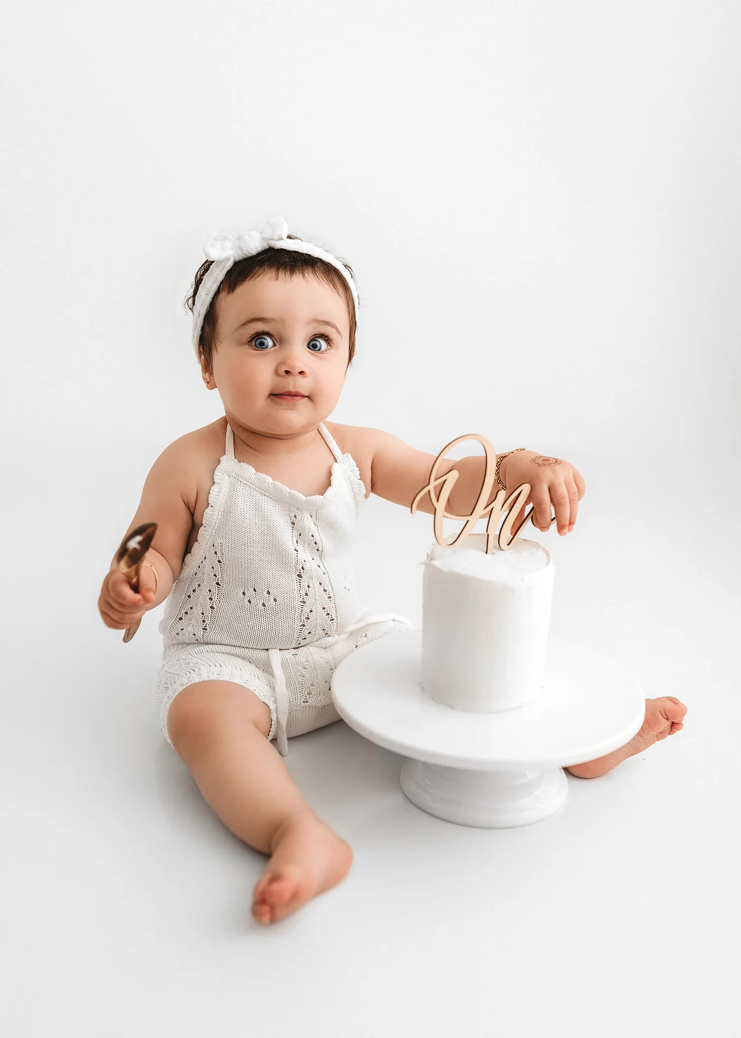 baby girl celebrating her first birthday eating cake, Cake smash photography, simple and clean cake smash photoshoot, first birthday photoshoot lincoln nebraska, omaha birthday photoshoot