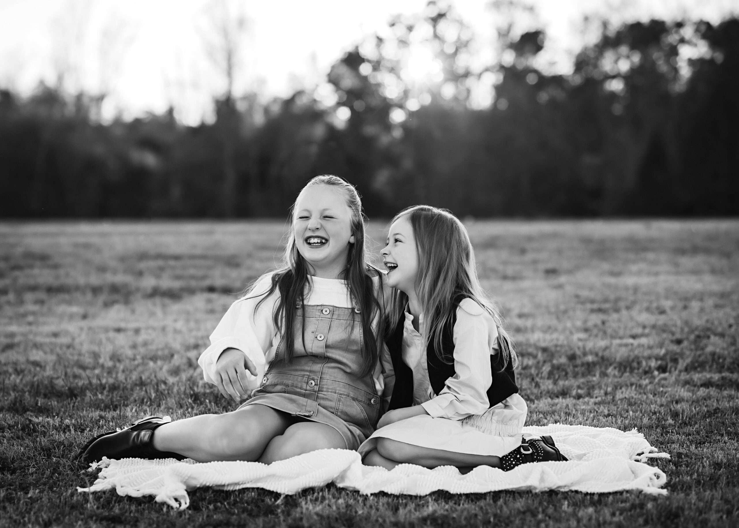 sisters laughing together during outdoor mini session, family pose ideas