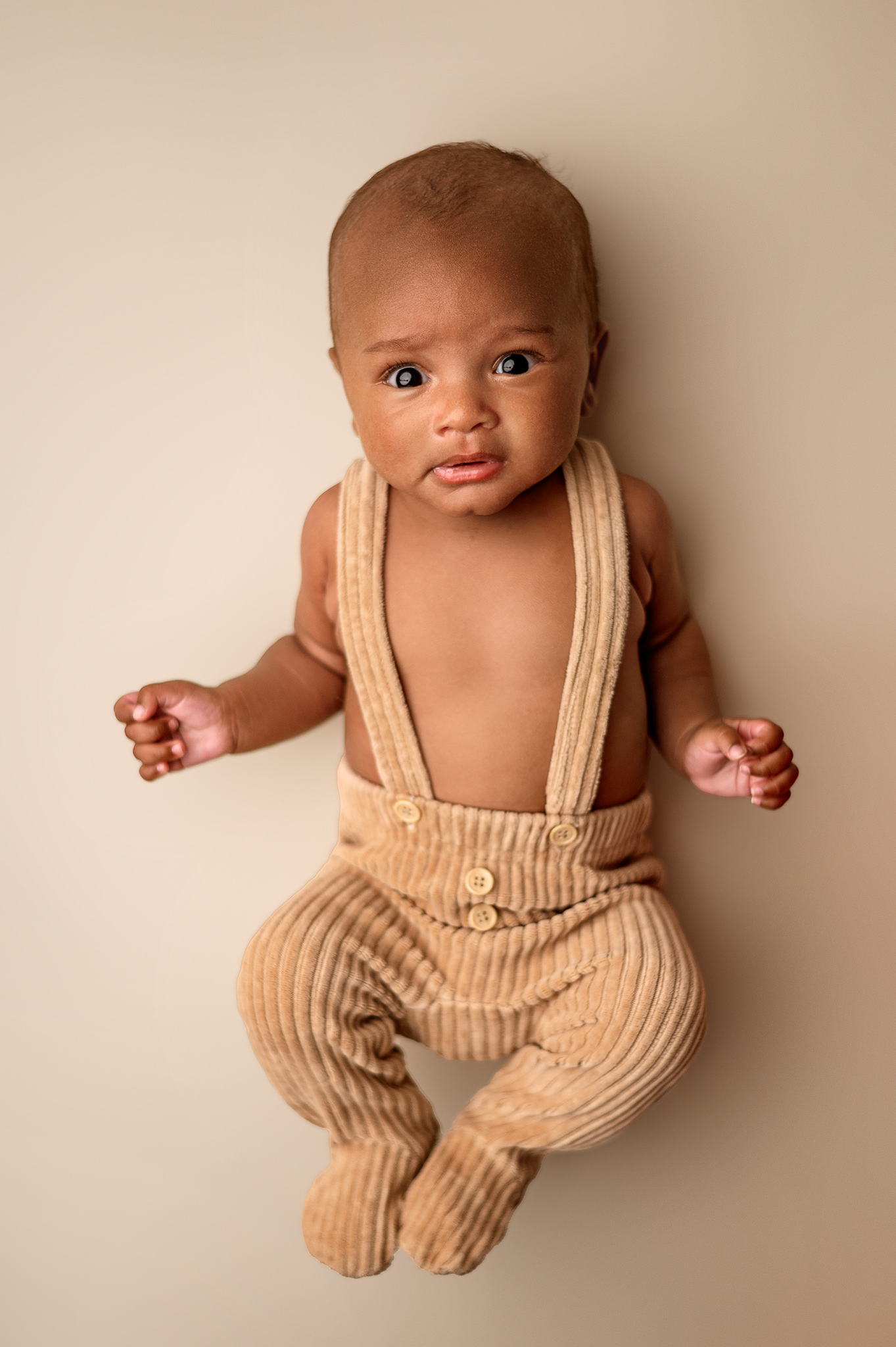 baby boy posed in cute suspenders on simple neutral backdrop, studio photographers in lincoln nebraska, baby portraits near me