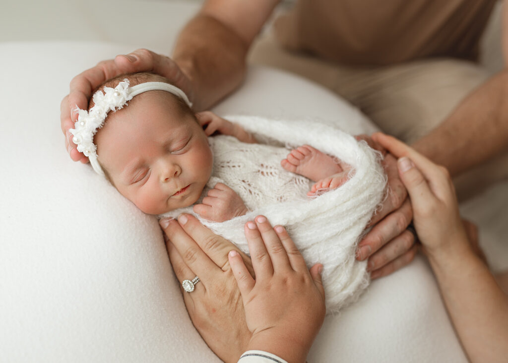 newborn photographer in indiana being held by her parents hands