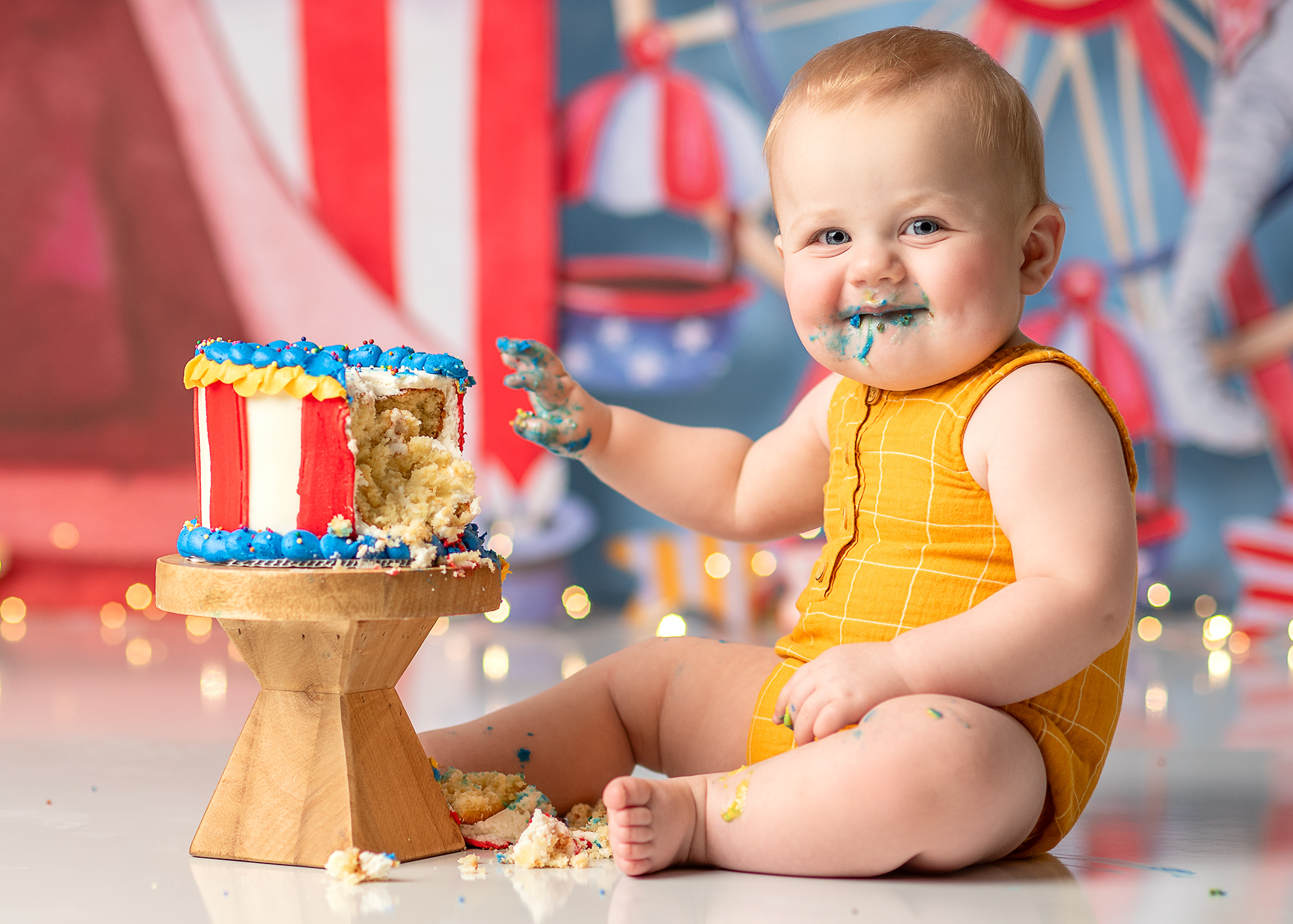 boy smiling with blue frosting around mouth during photoshoot for first birthday in lincoln nebraska