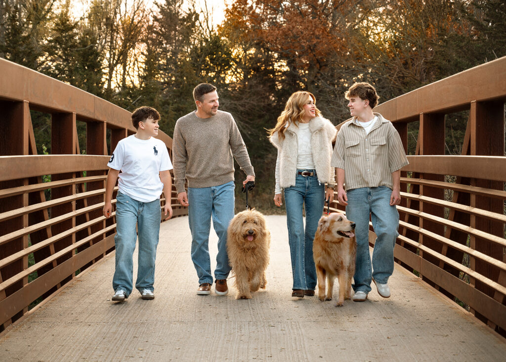 family walking on bridge with dogs during outdoor family photo session in indianapolis