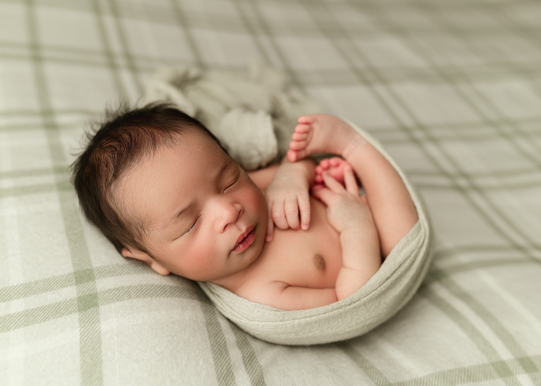 newborn posed on plaid fabric in indiana home