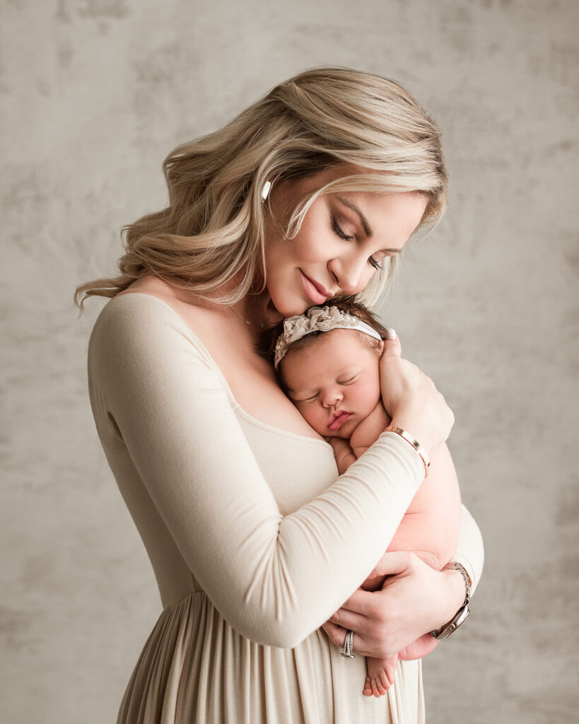 mom snuggling newborn daughter during in home newborn session indianapolis