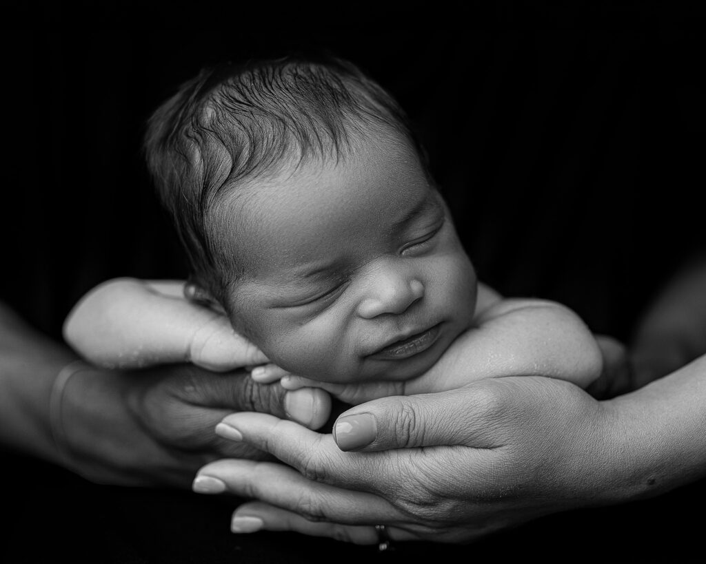 Baby posed perfectly in mom and dads hands to show how tiny he is