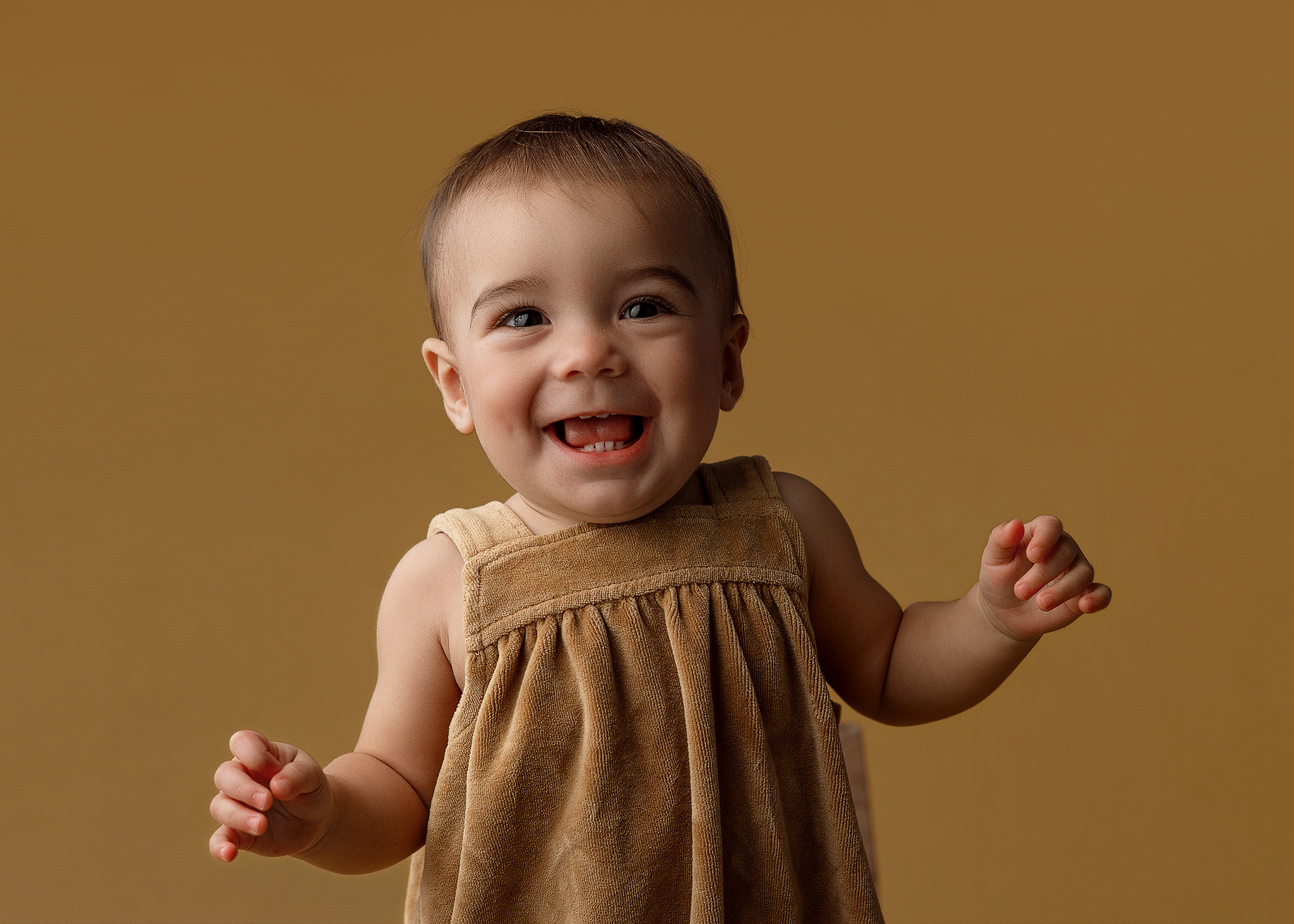 One year old baby in mustard yellow outfit during a milestone photography session by Indianapolis baby photographer