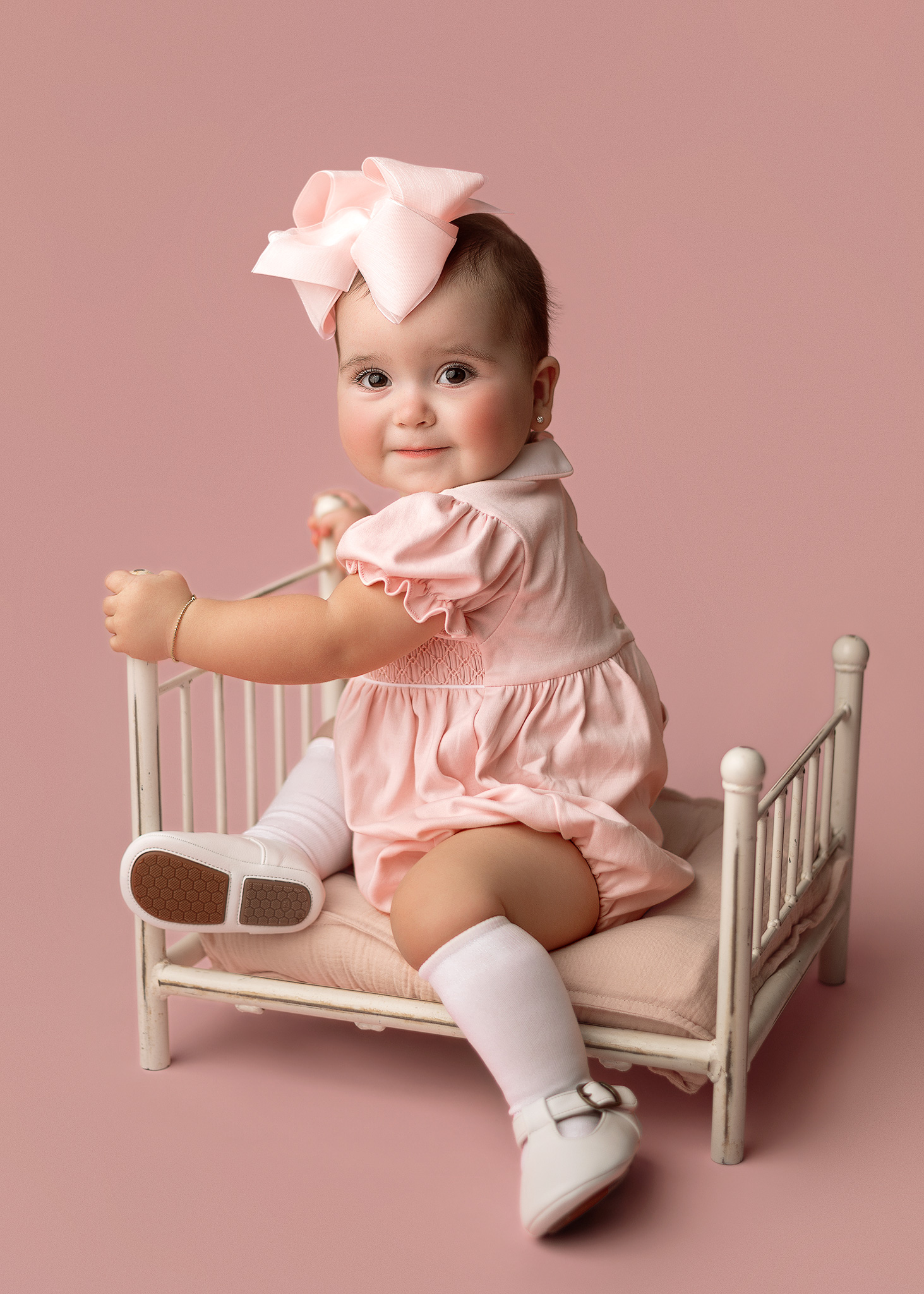 Baby girl celebrating her first birthday in light pink during a professional in-home milestone photography session